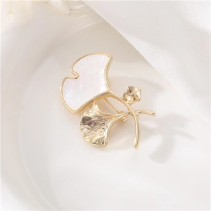 Broche élégante en forme de feuille de ginkgo dorée avec nacre sur soie blanche