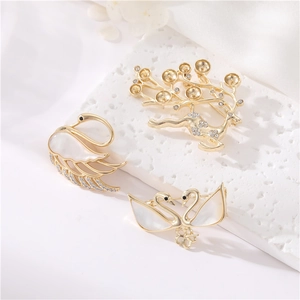 Détail de luxueuses broches cygne et cerf en or 14K avec zircons et nacre
