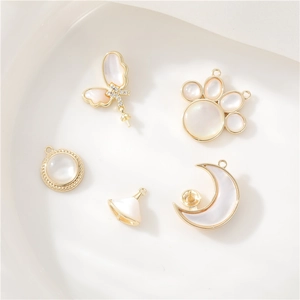 Detailed close-up of 14K gold plated butterfly, moon, and cat paw shell pendants