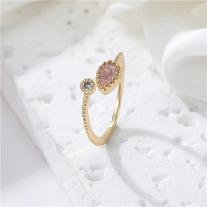 Detail of adjustable gold ring with pear-cut pink stone and millgrain texture band