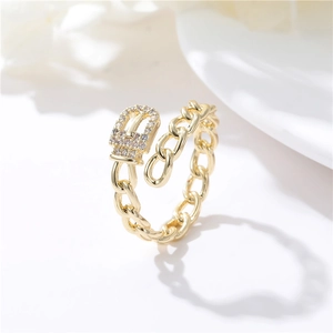 Detailed close-up of golden belt buckle ring with white zircon stones and chain design