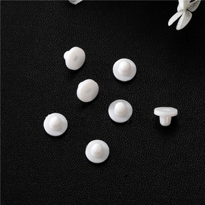 Macro shot of seven white silicone earring backs on black leather texture