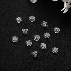 Detailed view of transparent silicone disc earring backs on premium black leather surface