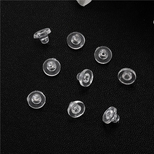 Detailed view of clear silicone earring backings on a textured black leather surface