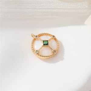 Macro view of 14k gold-filled pendant with green zircon and white mother of pearl inlay
