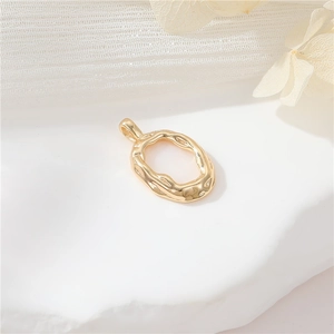 Macro shot of 14k gold-filled irregular textured oval pendant on a white stone base