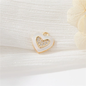 Macro detail of a 14k gold plated heart pendant with white enamel and sparkling zircons