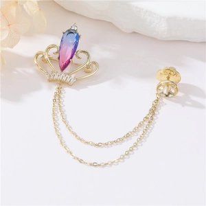 Detailed view of a golden crown brooch with gradient blue stone and elegant double chains
