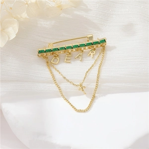 Elegant gold brooch with emerald stones, DEAR charms and delicate double tassels