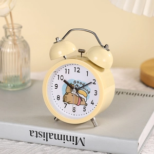Close-up of yellow capybara twin bell alarm clock on a book in cozy home setting
