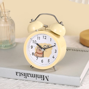 Retro yellow metal double bell alarm clock with cute capybara dial on a book