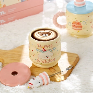 Close-up of cream ceramic Capybara mug with pink lid and cute 3D puppy spoon