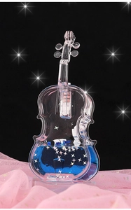 Detailed macro of violin-shaped liquid sand ornament with blue fluid and star sequins