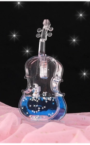 Close-up of violin-shaped ornament with blue liquid, stars, and an astronaut inside