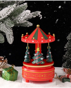 Close-up of a festive Christmas carousel music box with mini trees on snowy background