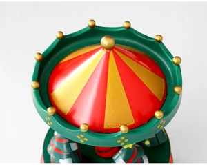 Top detail of Christmas carousel music box featuring festive red stripes and gold stars