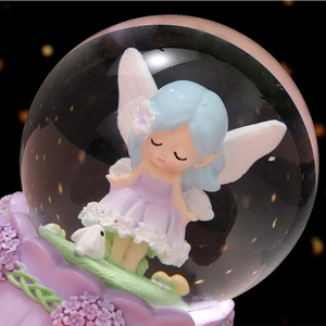 Boule de cristal féerique lumineuse avec ange et lapin sur socle floral en résine