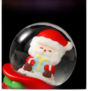Close-up of Santa Claus inside a crystal ball holding a blue gift box with festive base
