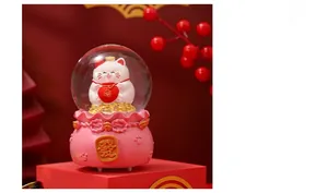 Close-up of Lucky Cat crystal ball music box with festive pink base and gold character