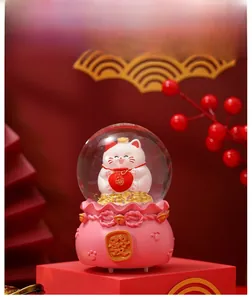 Macro view of Maneki Neko crystal ball with pink resin base and golden lucky coin detail
