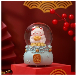 Close-up of crystal ball with fortune cat and golden coins on blue money bag base