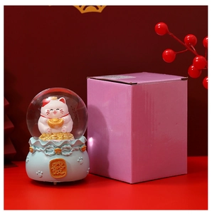 Close-up of Lucky Cat crystal ball with gold ingot and festive gift packaging box