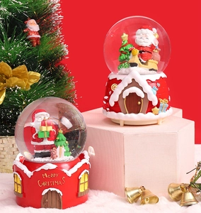 Close-up of Santa Claus snow globe with Merry Christmas text on a red house base