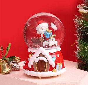 Detail of Santa Claus inside a festive crystal ball with red snow house resin base