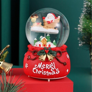 Detail of Santa Claus sleigh snow globe with a red gift bag base and festive bells