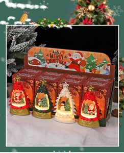 Détail de quatre ornements globes d'eau de Noël lumineux à LED avec emballage festif