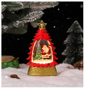 Gros plan d'une lampe cristal en forme de sapin avec scène du Père Noël illuminée