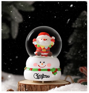 Détail d'une boule à neige Père Noël avec socle bonhomme de neige et texte de Noël