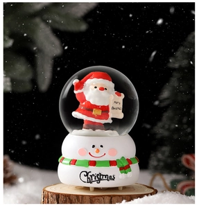 Détail d'une boule à neige Père Noël avec base bonhomme de neige sur fond de bois rustique
