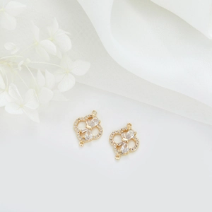 Detailopname van 14k vergulde klaverhangers met zirkonia en een elegant strikje