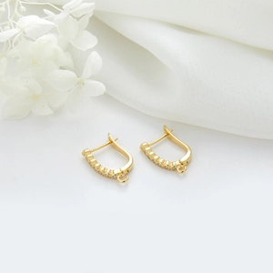 Détail des boucles d'oreilles dorées avec zircon blanc sur soie blanche