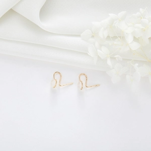 Minimalistische gouden oorhaken met siliconen kussentjes op witte zijde en bloemen