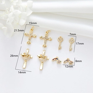 Detailed view of four gold-plated pendants including cross, heart key and rainbow zircon