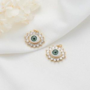 14K gold plated evil eye pendant with green iris and white zircon stones on white fabric