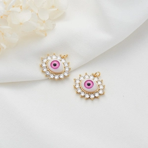 Close-up of 14K gold plated evil eye charms with pink resin and cubic zirconia stones