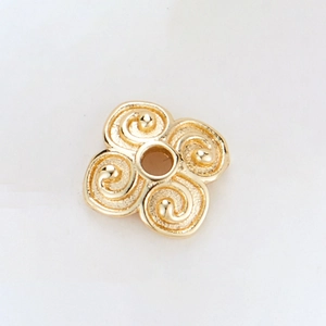 Macro detail of 14k gold-plated flower spacer bead with spiral texture and center hole