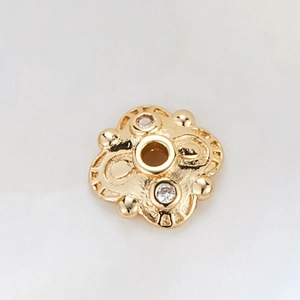 Macro shot of 14k gold plated bead spacers with zircon accents and hollow floral pattern