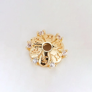 Macro view of 14k gold plated spacer bead with zircon petals and engraved symbols