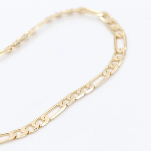 Makro-Detail einer 14k vergoldeten Figaro-Kette mit polierter 3+1 flacher Gliederstruktur