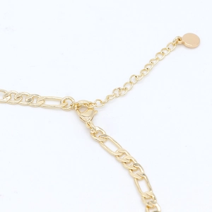 Detail einer 14k vergoldeten Figaro-Kette mit Karabinerverschluss und Verlängerung