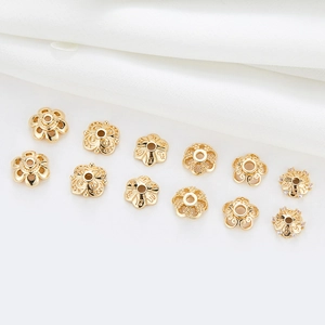 Assorted 14k gold plated flower spacer beads with zircons on white silk background