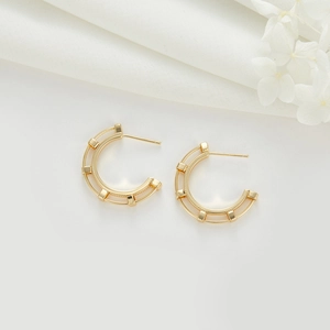 Détail de boucles d'oreilles dorées en C avec architecture double rail et tiges en argent 925