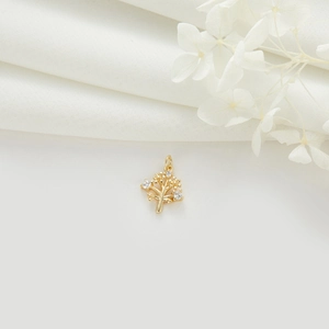 Pendentif sapin de Noël doré avec zircons et anneau sur fond de tissu blanc élégant