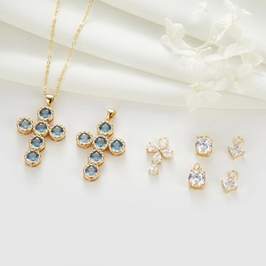 Elegant gold cross pendants and crystal jewelry charms set on white silk background