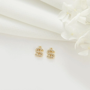 Macro detail of 14k gold-plated dollar sign pendants with shimmering crystals for DIY jewelry