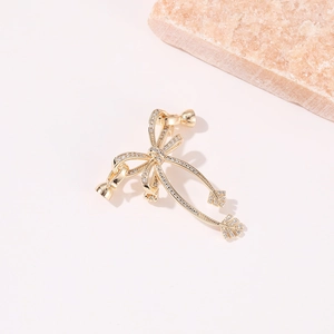 Détail macro du pendentif nœud doré avec zircons micro-pavés et pampille élégante
